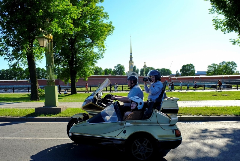На фото: Марина Козикова на золотом мотоцикле едет напротив Петропавловской крепости