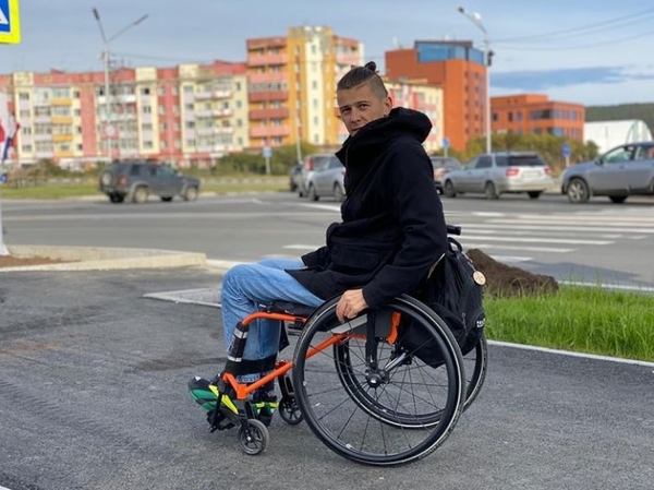 На фото: Денис Антипов на коляске на асфальтовой дороге на улице города