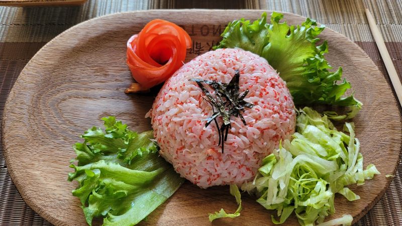 На фото: блюдо из риса и крабового мяса на деревянной тарелке