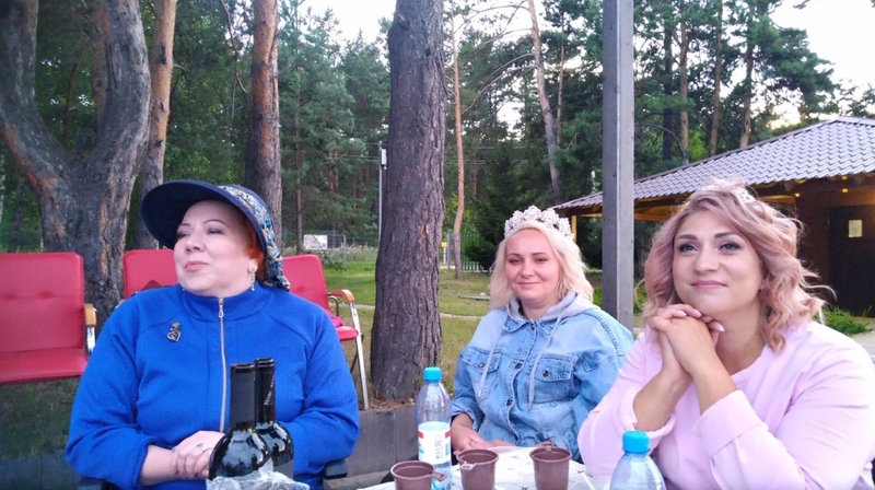 На фото: Марина Козикова вместе с другими участницами сидит за столом под открытым небом