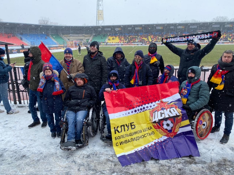 На фото: участники клуба болельщиков с флагами и шарфами на стадионе, засыпанном снегом