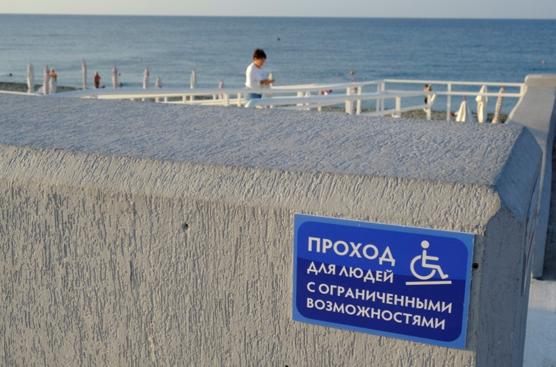 На фото: спуск на пляж для маломобильных отдыхающих в Сочи. Табличка с надписью: проход для людей с ограниченными возможностями