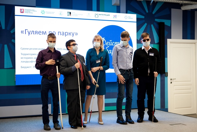 На фото: команда проекта "Гуляем по парку" стоит на сцене рядом с большим экраном с презентацией проекта. В команде - четверо молодых людей и девушка. 