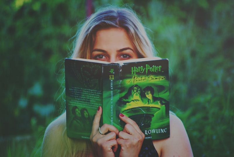 На фото: девушка с раскрытой книгой о Гарри Поттере в руках