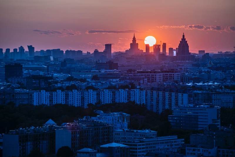 На фото: Москва, силуэты домов на закате, солнце садится за горизонт